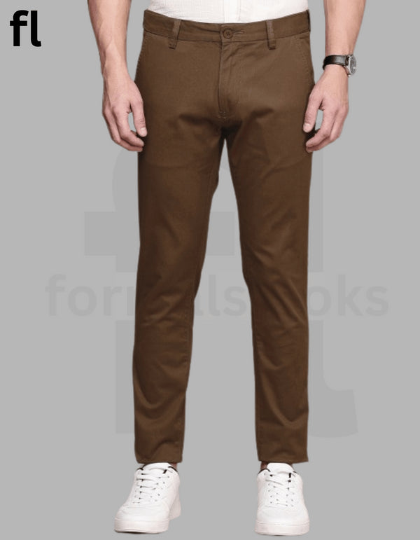 A pair of brown cotton pants with a smart fit, displayed on a model against a grey background, with the model wearing white shoes.